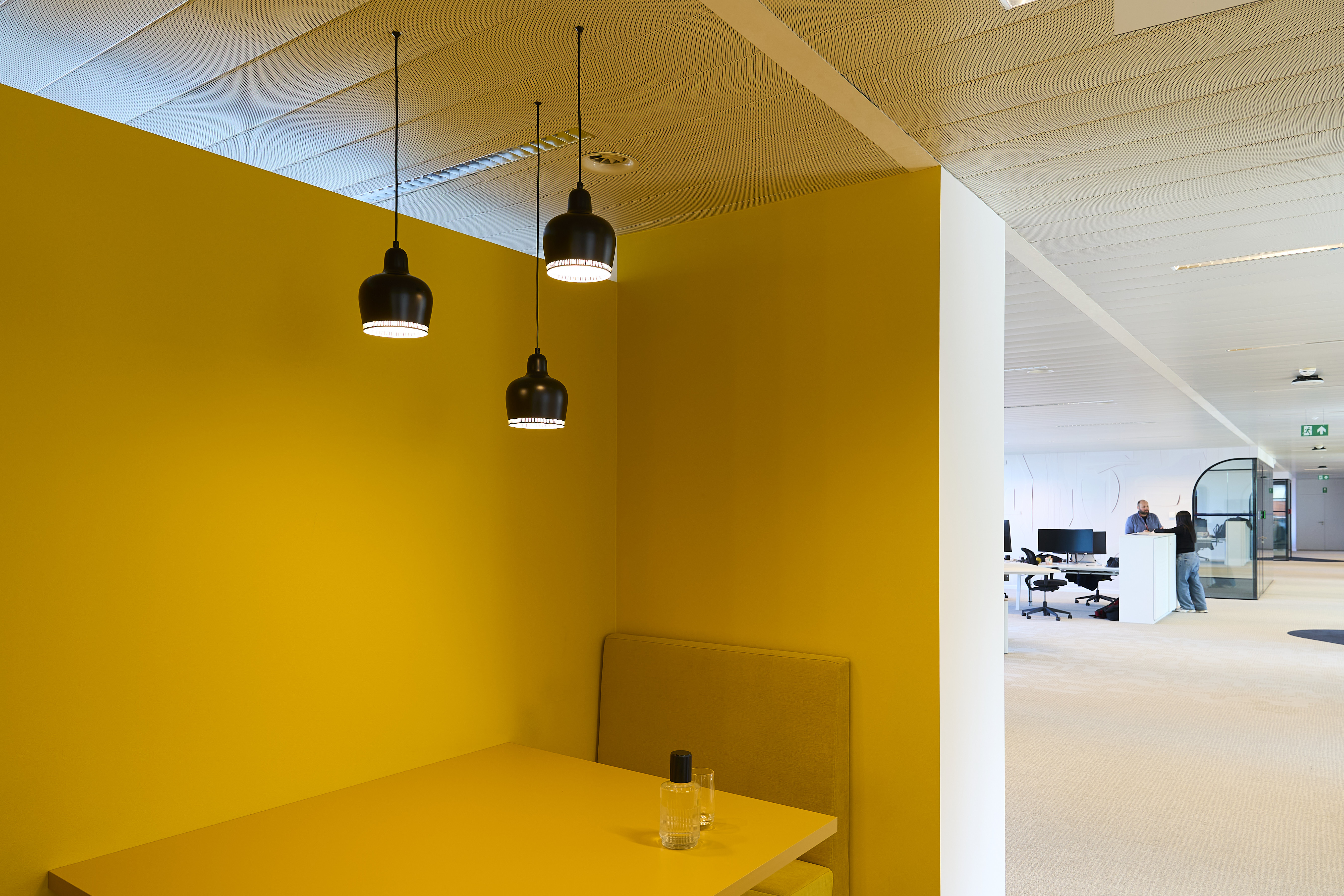 une table jaune avec deux lumières noires suspendues au plafond