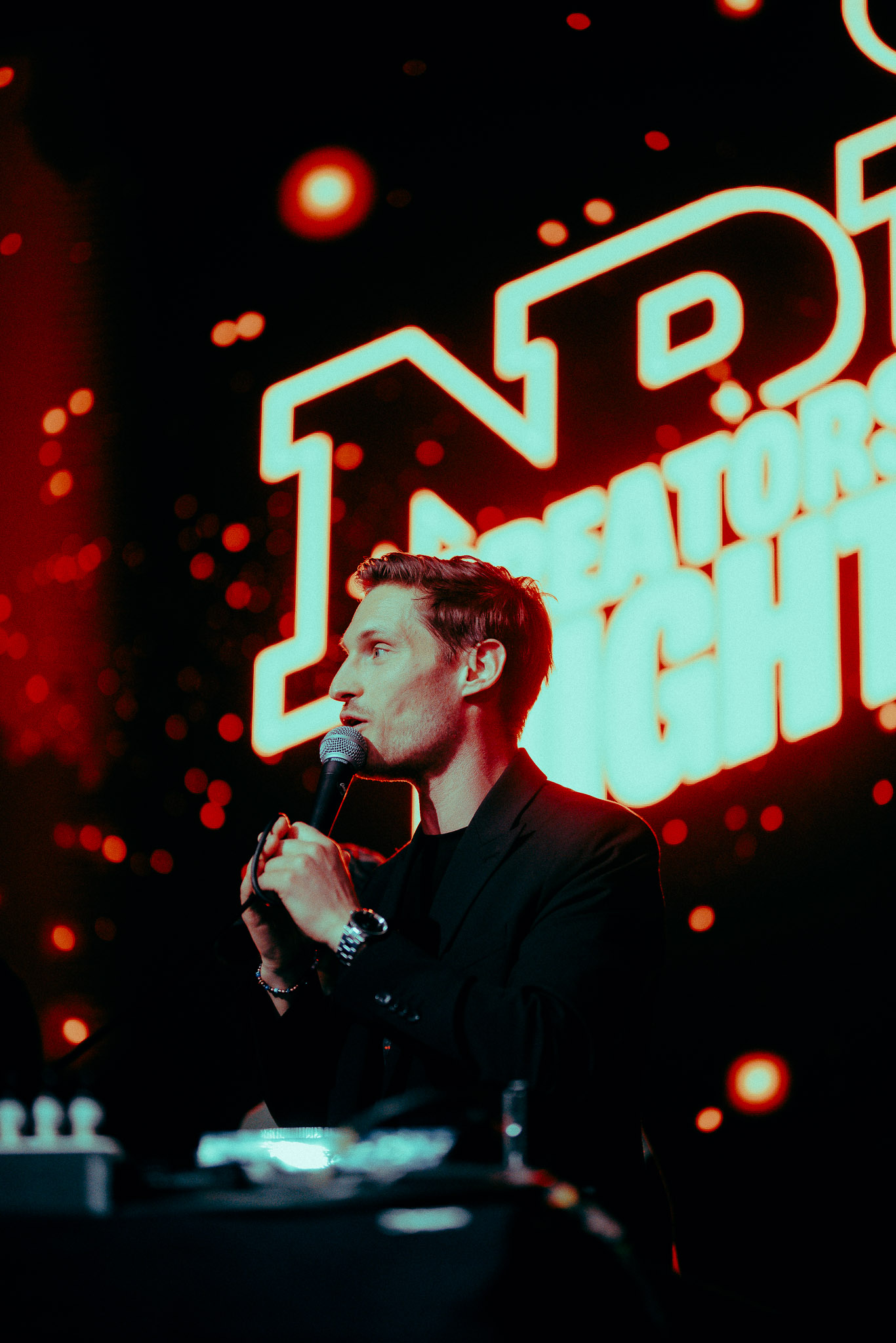 un homme tenant un microphone devant une enseigne éclairée